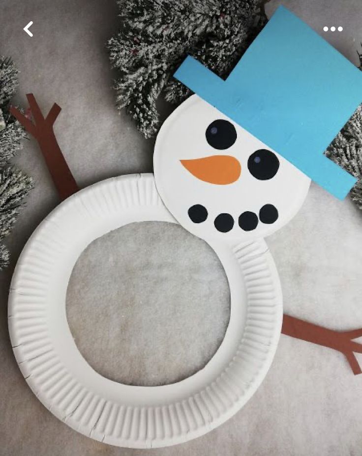 a paper plate with a snowman on it next to some fake trees and branches