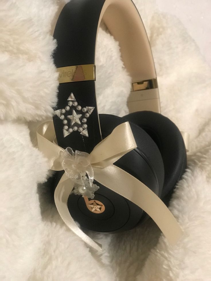 black headphones with white bows on them sitting on a furry surface next to a teddy bear