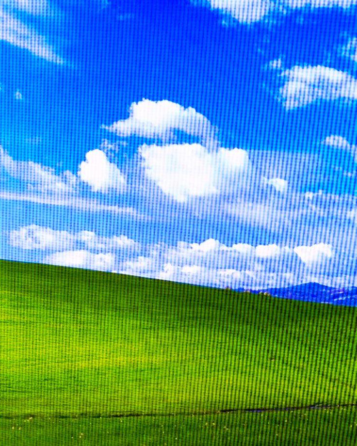 a man is flying a kite in the air on a green field with blue sky and clouds