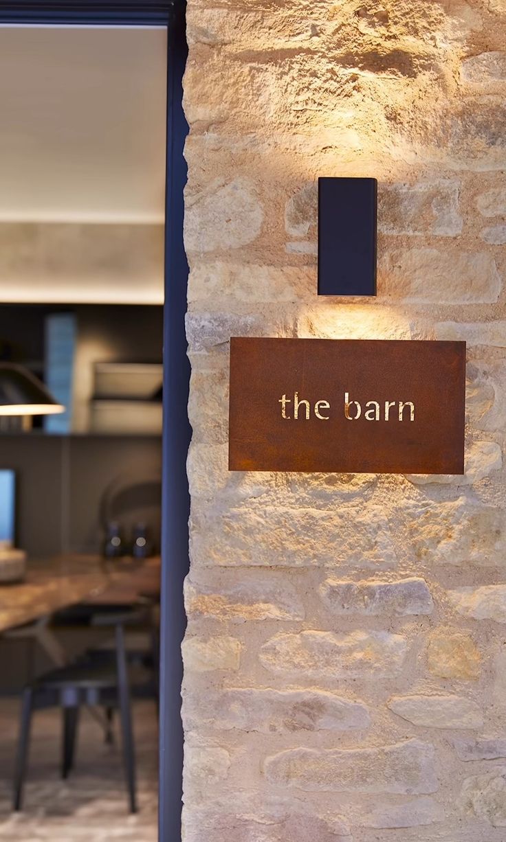 the barn sign is lit up in front of a stone wall and dining room table