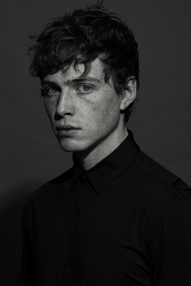 a black and white photo of a man with freckled hair looking at the camera