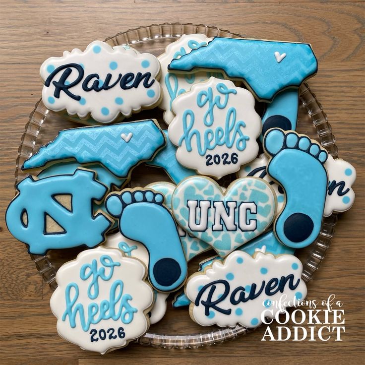 cookies decorated with blue and white icing are on a glass plate in front of a wooden table