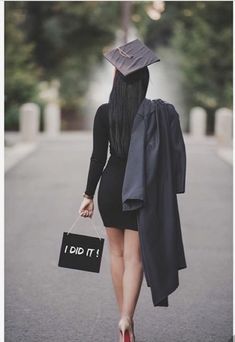 a woman with a graduation cap and gown walking down the street holding a sign that says i did it