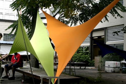 two people sitting on a bench in front of colorful kites hanging from the trees