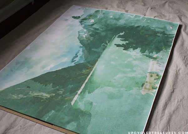 a painting is laying on top of a sheet of paper with the image of a tree reflected in it