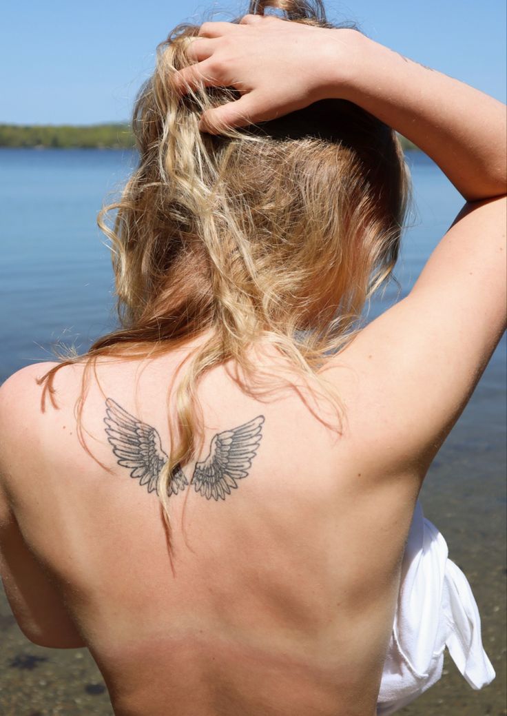 the back of a woman's head with wings on her upper and lower back