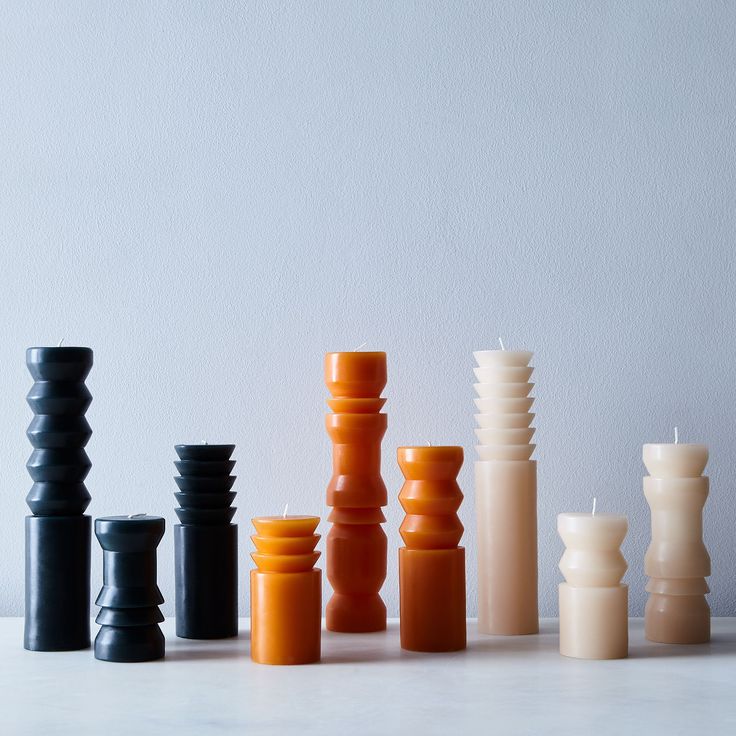 an assortment of candles sitting on top of a white table next to eachother