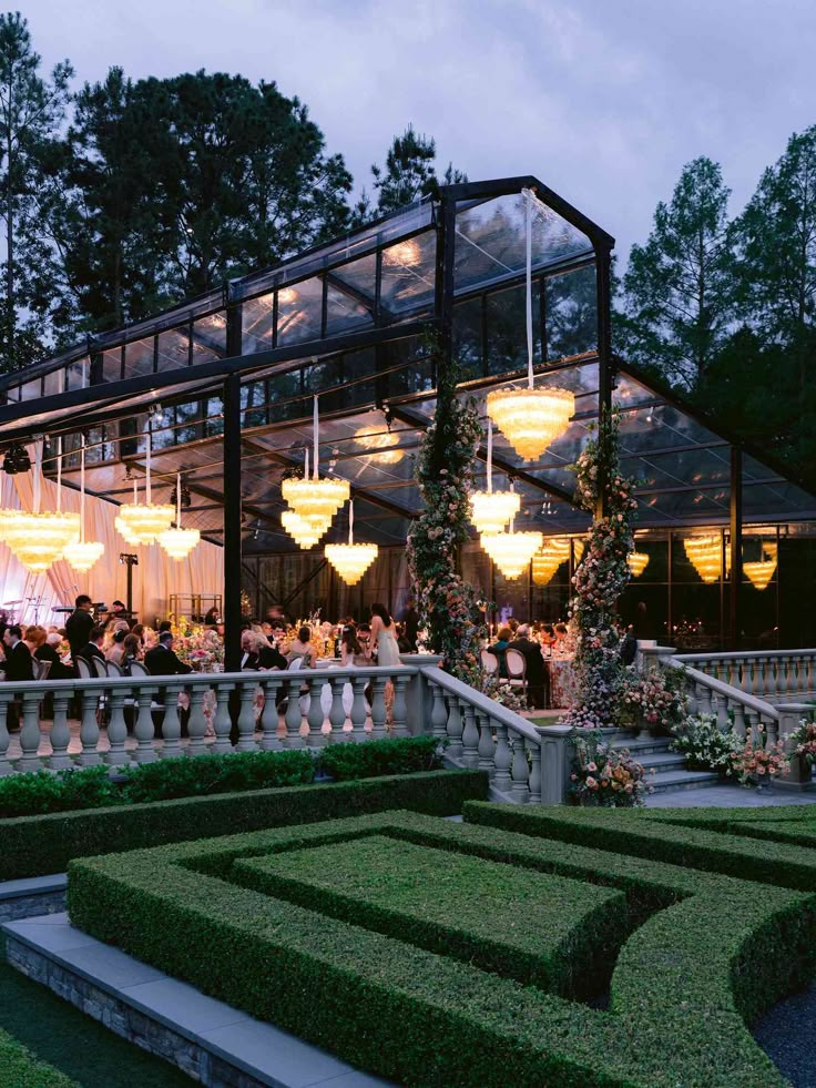 an outdoor dining area with tables and chandeliers in the background at night time