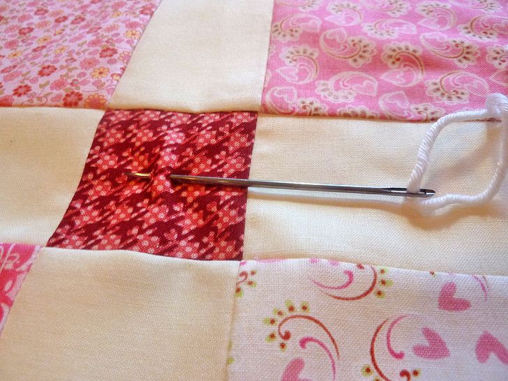 a pair of scissors cutting through the center of a piece of fabric with pink and white designs on it