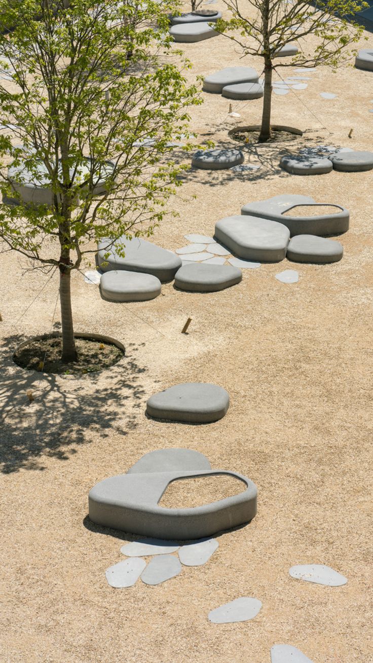 an empty park with benches and trees in the middle, surrounded by graveled stones