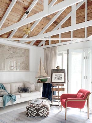 a living room with white furniture and wooden ceilings