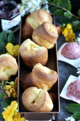 some pastries are in a box on a table next to flowers and water bottles