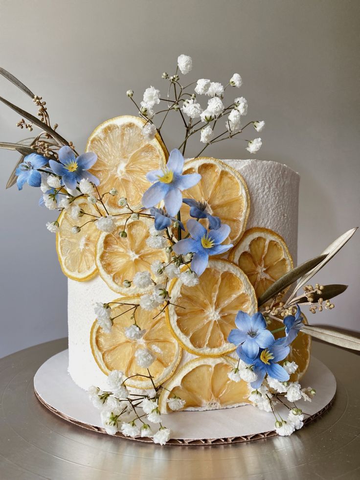 a white cake with lemon slices and blue flowers