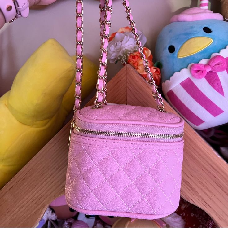 a pink purse sitting on top of a wooden table next to stuffed animals and toys