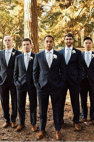 a group of men standing next to each other wearing suits and ties with trees in the background