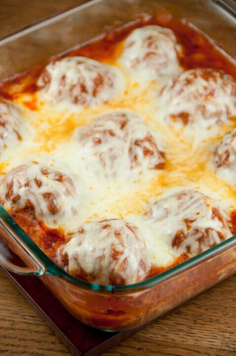 a casserole dish with meatballs and cheese in it on a wooden table