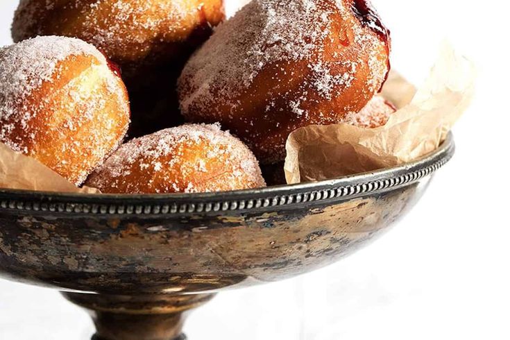 powdered sugar covered donuts in a metal bowl