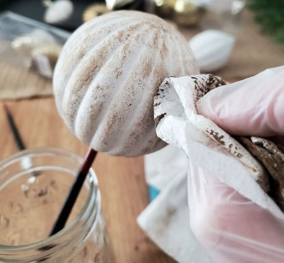 a person in gloves is holding an object with something on it and the other hand has a glass jar full of stuff