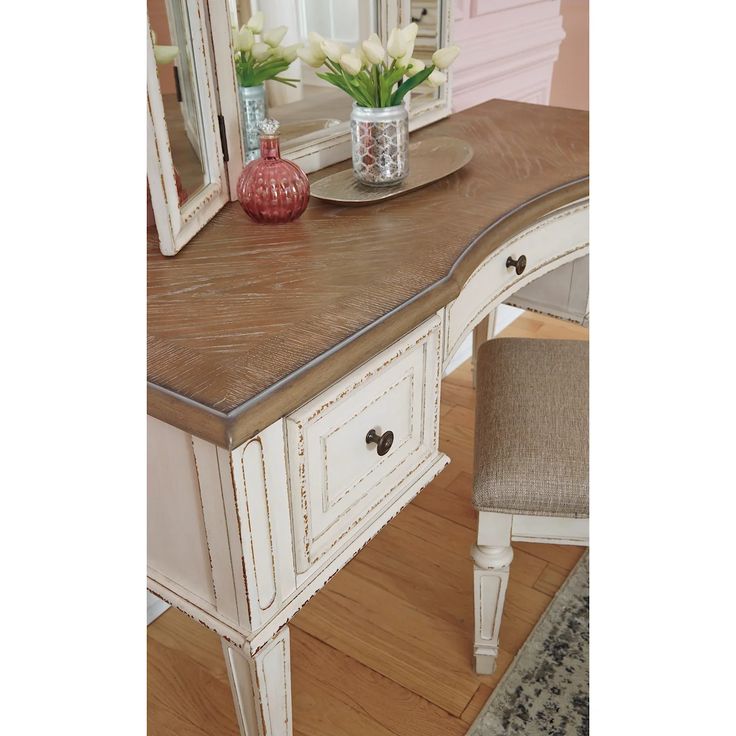 a white desk with a mirror and flowers on it