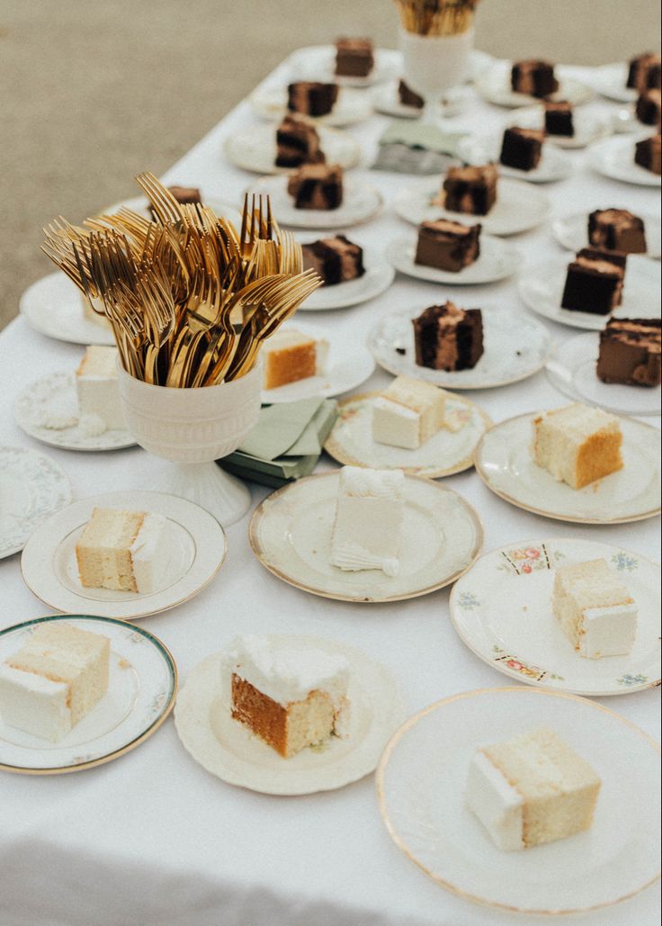 a table topped with lots of white plates covered in cakes and desserts next to each other