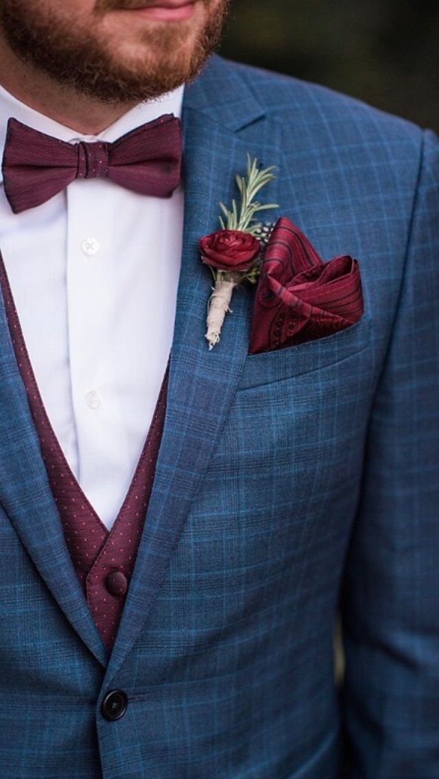 a man in a blue suit with a red bow tie and boutonniere