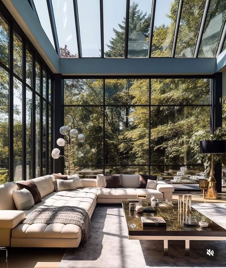 a living room filled with lots of furniture next to large glass windows on the wall