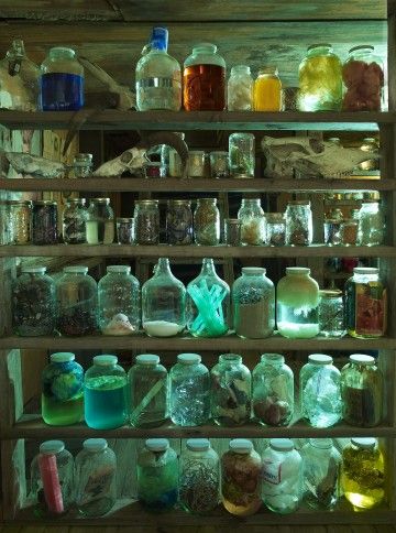 an old shelf filled with lots of bottles and jars on top of wooden shelves next to each other