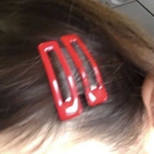 a close up of a person's hair with two red clips on it