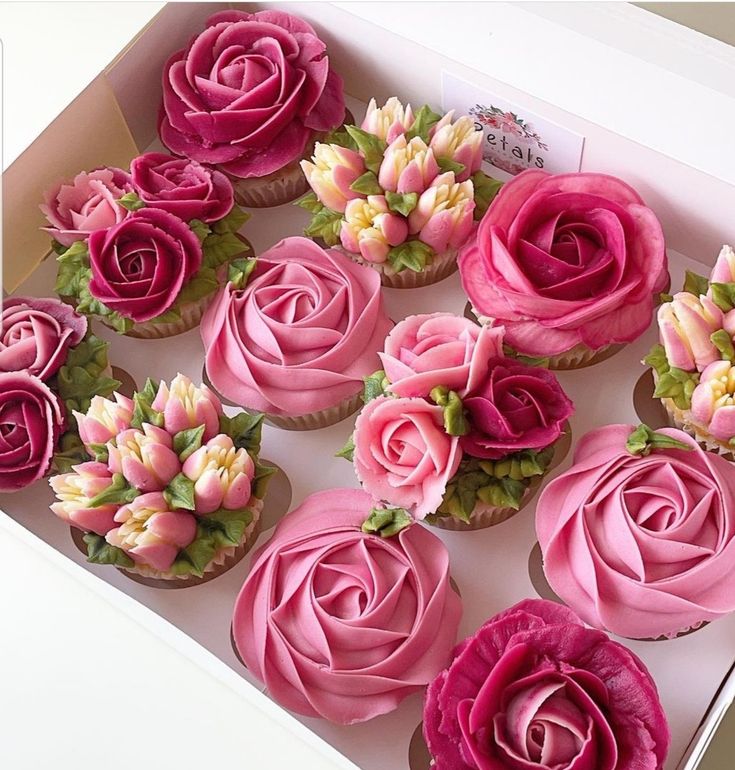 cupcakes with pink frosting and flowers in a box