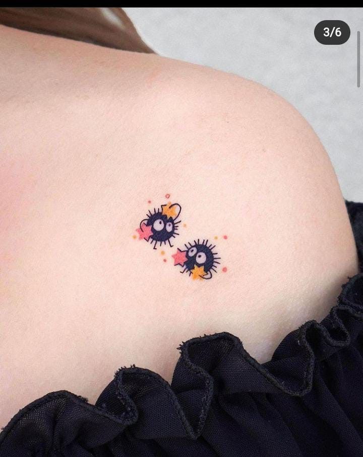 the back of a woman's shoulder with two small tattoos on her left side