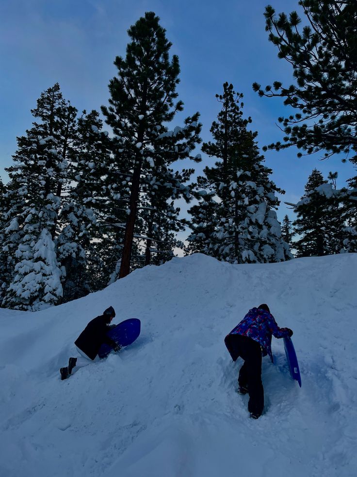 two snowboarders are laying in the snow with their boards on their back legs