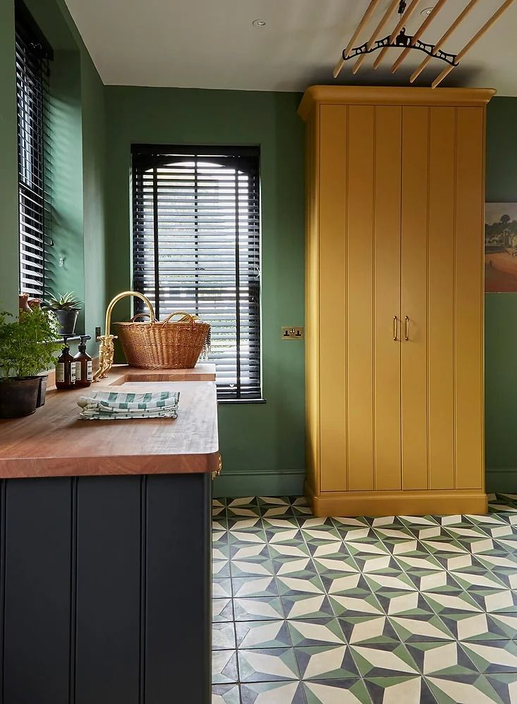 a kitchen with green walls and yellow cupboards in the center, tiled flooring