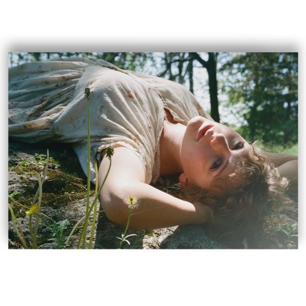 a woman laying down on the ground with her hands behind her head and eyes closed