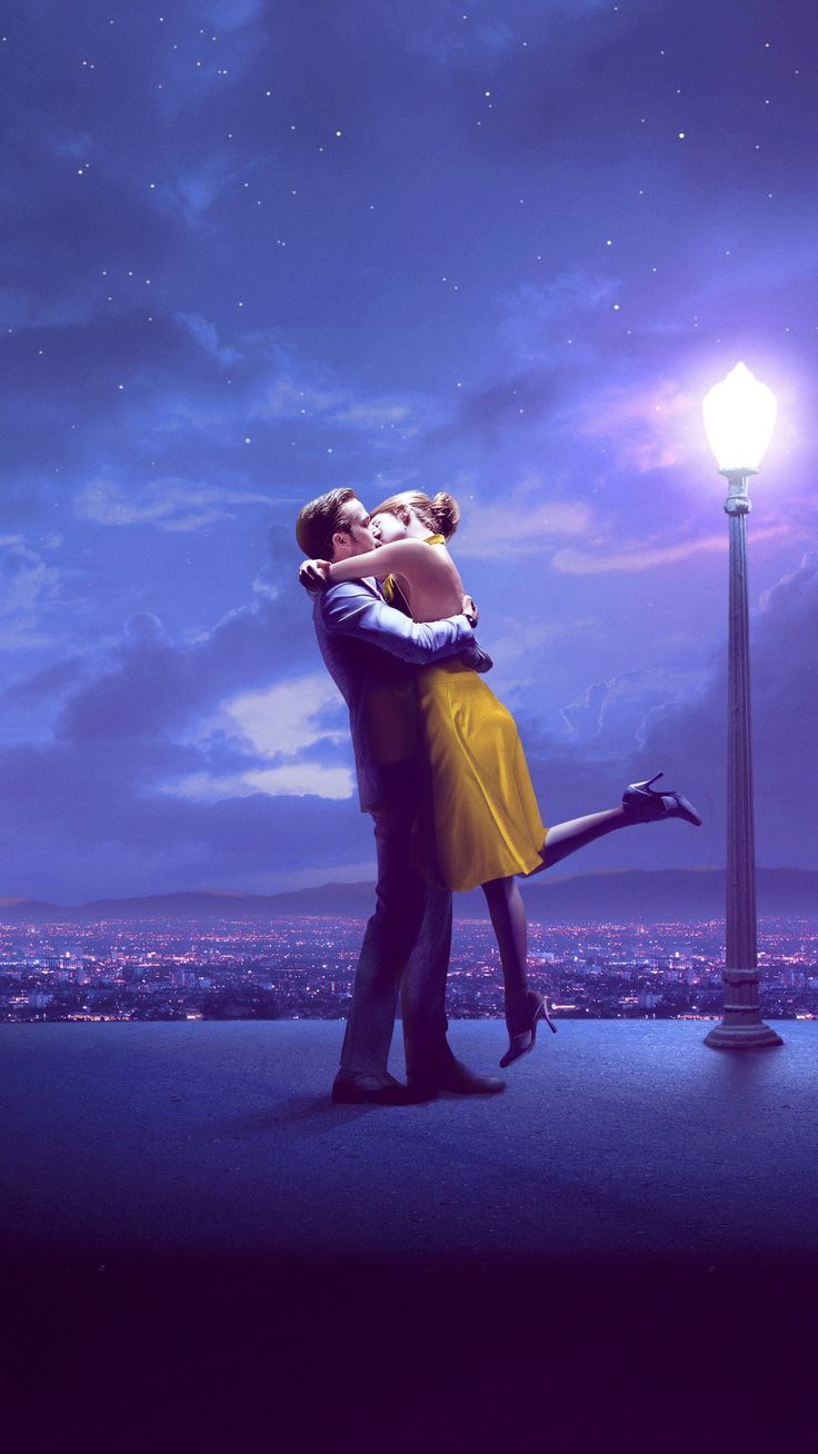 a man and woman kissing in front of a street light with the night sky behind them