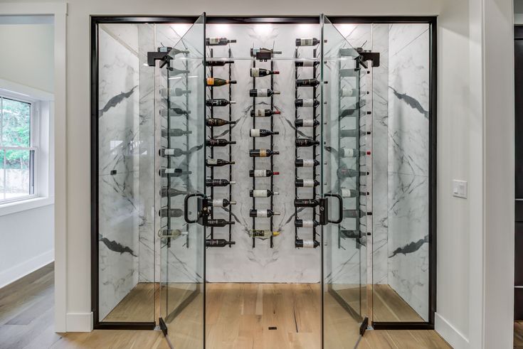 a glass display case filled with lots of wine glasses in a white and black room