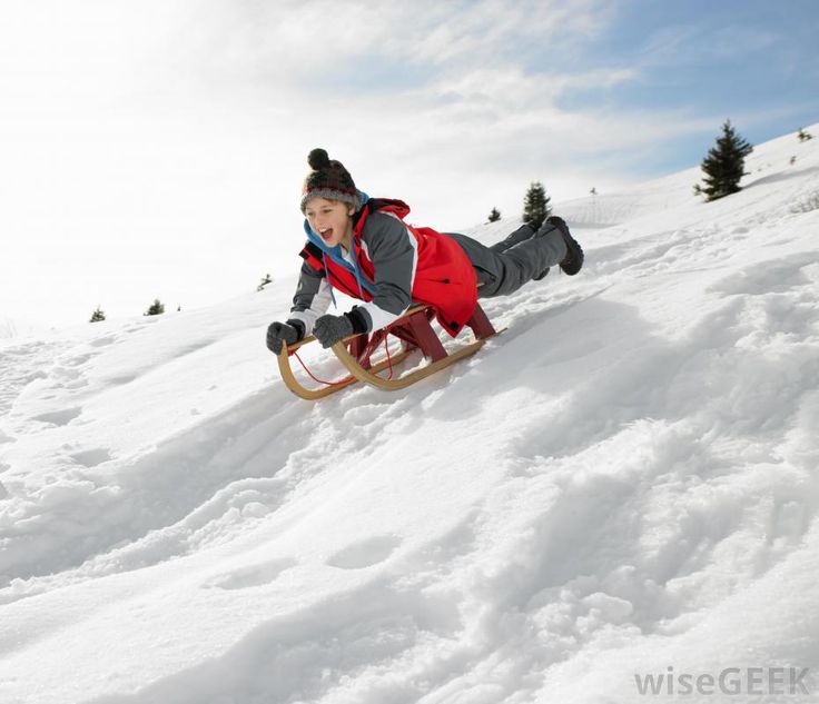 a young boy riding a sled down a snow covered slope