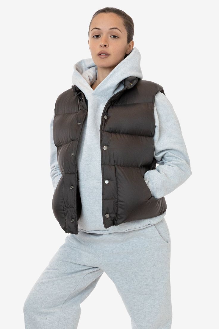 This made in U.S.A. puffer vest is the perfect layering piece for Los Angeles winters. Composed of a super fluffy polyester filling with a 100% nylon shell, this style features a reinforced snap-button closure, and 2 large pockets. We gave this style a wide, boxy fit with a mockneck for essential warmth. Try sizing up for an even more oversized fit. Made in Los Angeles, Calif. Our experienced sewers earn up to $25 an hour and no less than $16; additionally workers have healthcare benefits for le Solid Puffer Vest For Cold Weather, Nylon Vest For Layering In Fall, Cold Weather Solid Puffer Vest, Solid Color Puffer Vest For Cold Weather, Fall Nylon Vest For Layering, Fall Layering Nylon Vest, Sporty Winter Vest For Layering, Nylon Vest For Winter And Cold Weather, Nylon Vest For Cold Weather And Winter