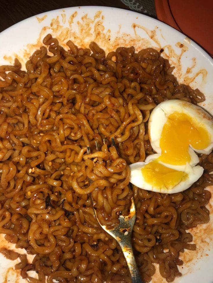 a plate with noodles and an egg on it, ready to be eaten by someone