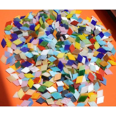 a pile of multicolored glass tiles sitting on top of an orange surface