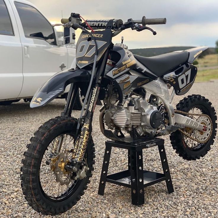 a dirt bike sitting on top of a stand in front of a white pickup truck