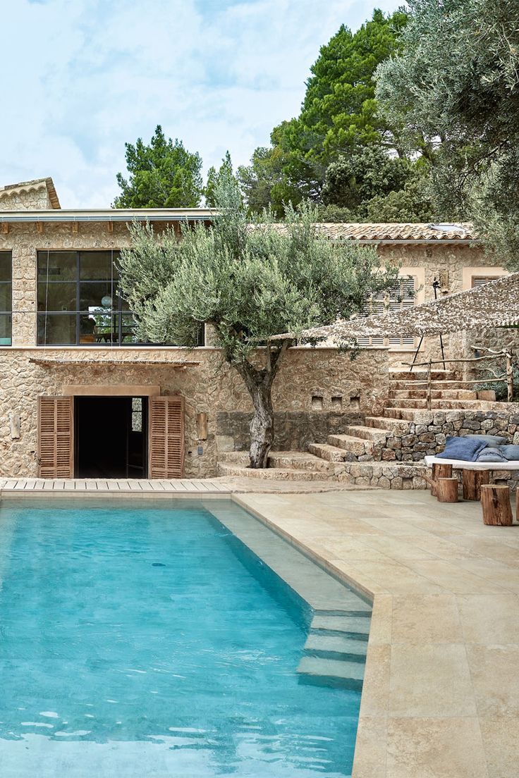 an outdoor swimming pool with steps leading up to it and a stone building in the background