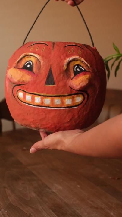 a person holding a pumpkin with a face painted on it