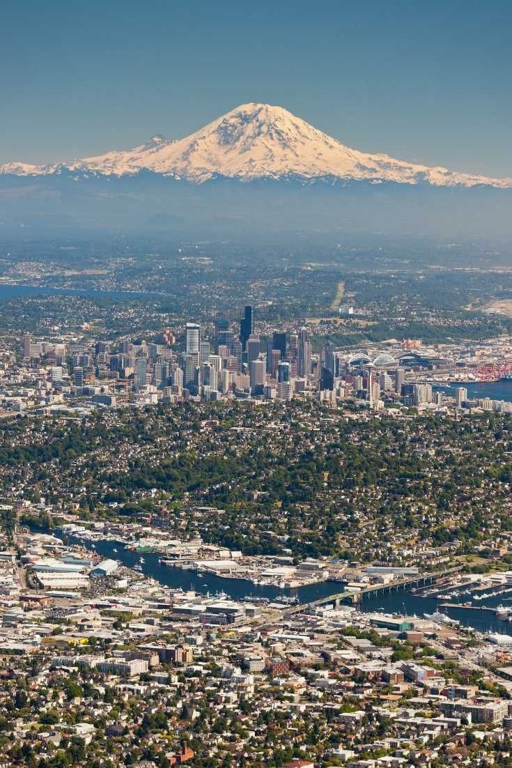 an aerial view of a city with mountains in the background and snow - capped peaks