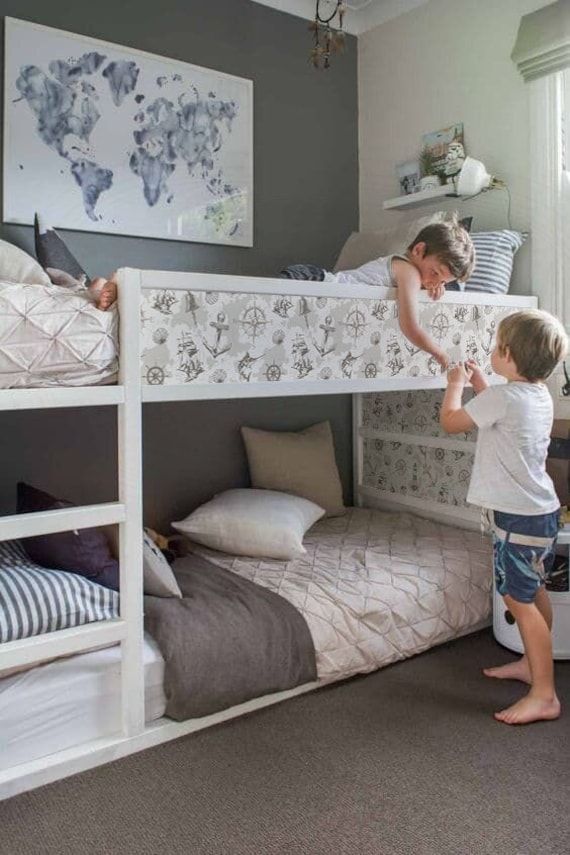 a woman and child are standing in front of bunk beds with their feet on the bed