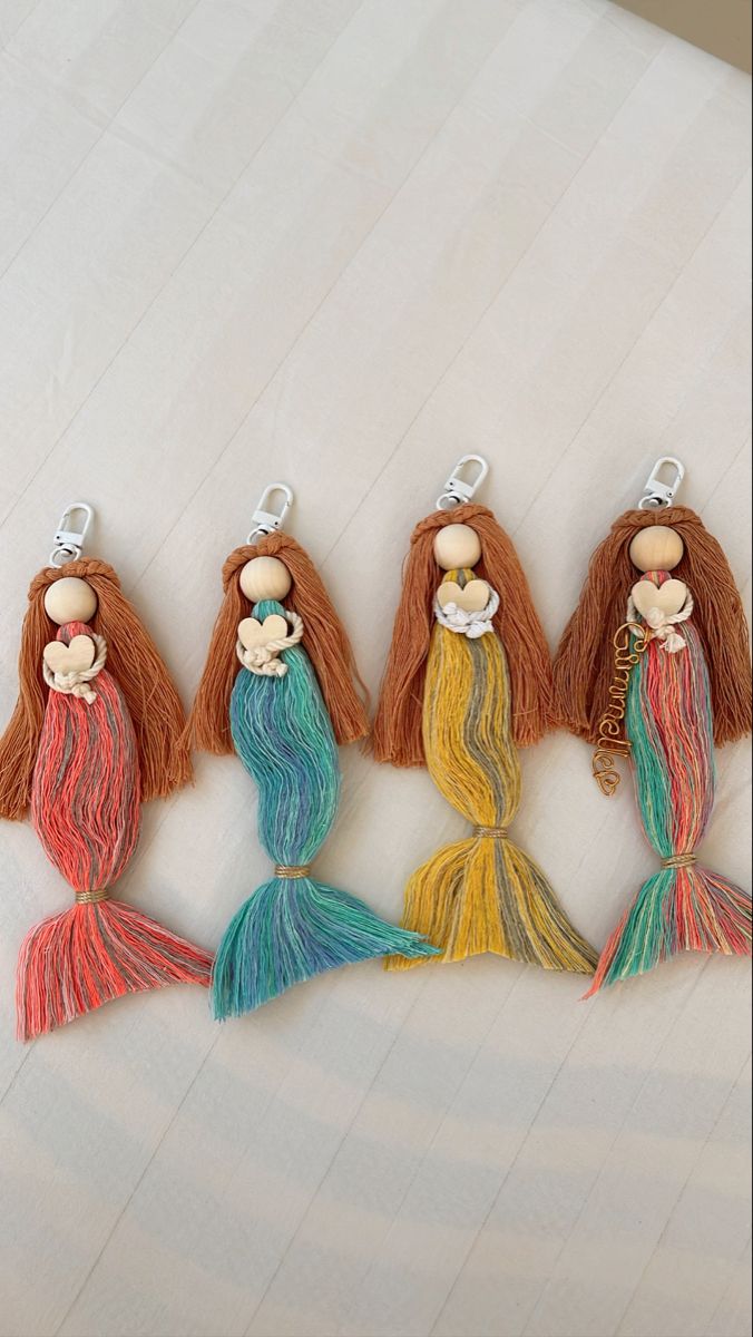 four little mermaids with long hair are hanging on a white surface and one is wearing a necklace