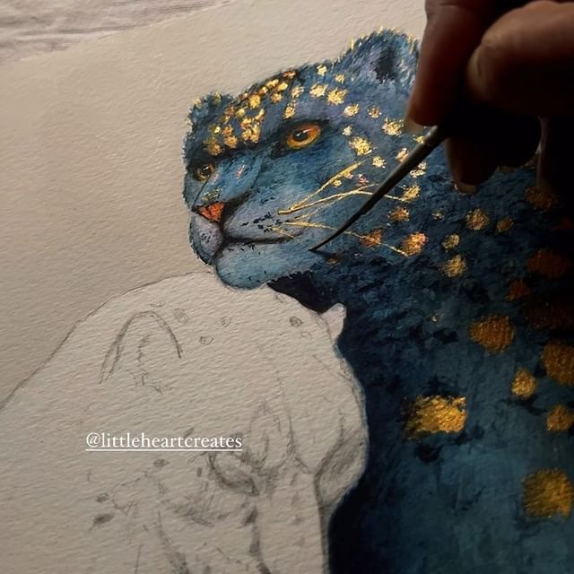 a person is painting a blue tiger with gold glitters