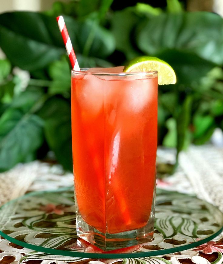 a drink with a straw in it sitting on a table next to a green plant