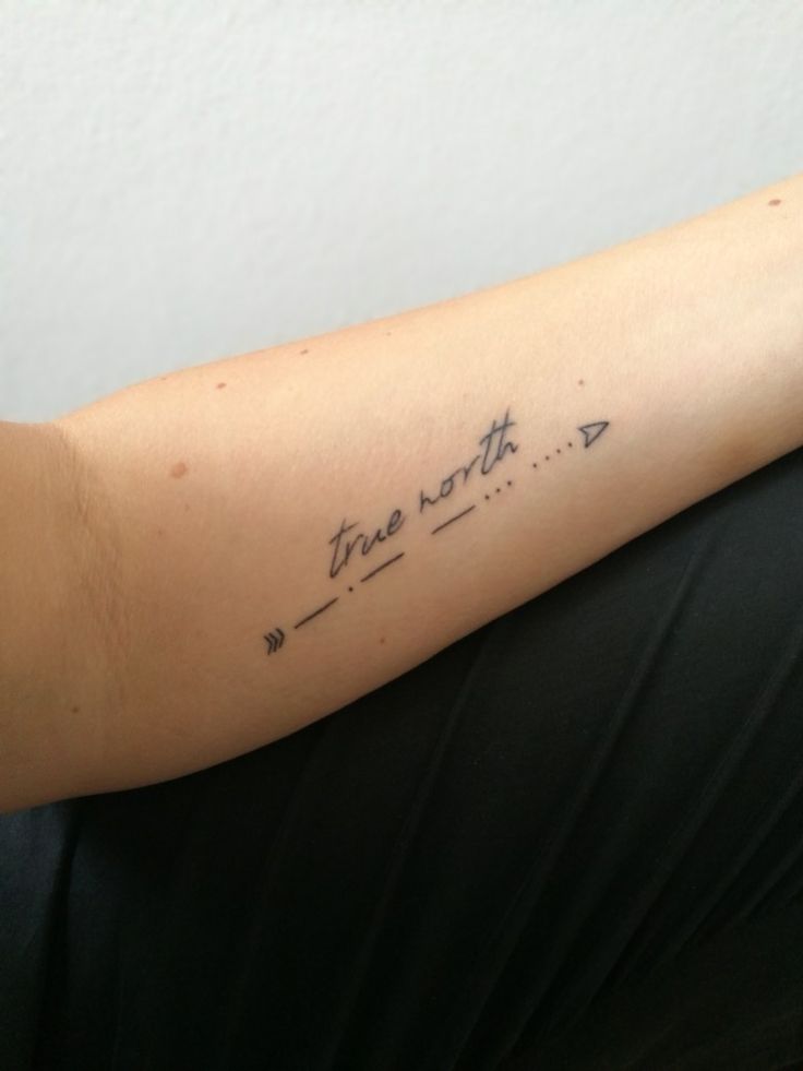 a woman with a tattoo on her arm that says true north