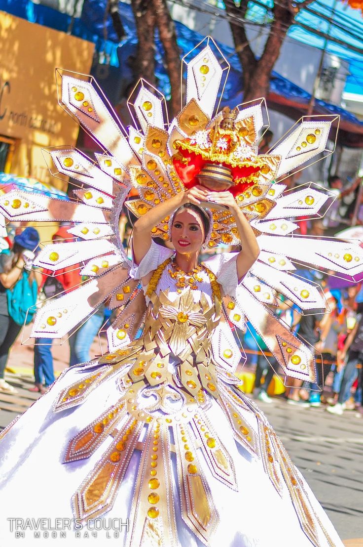 a woman in a white and gold costume holding a red heart on top of her head