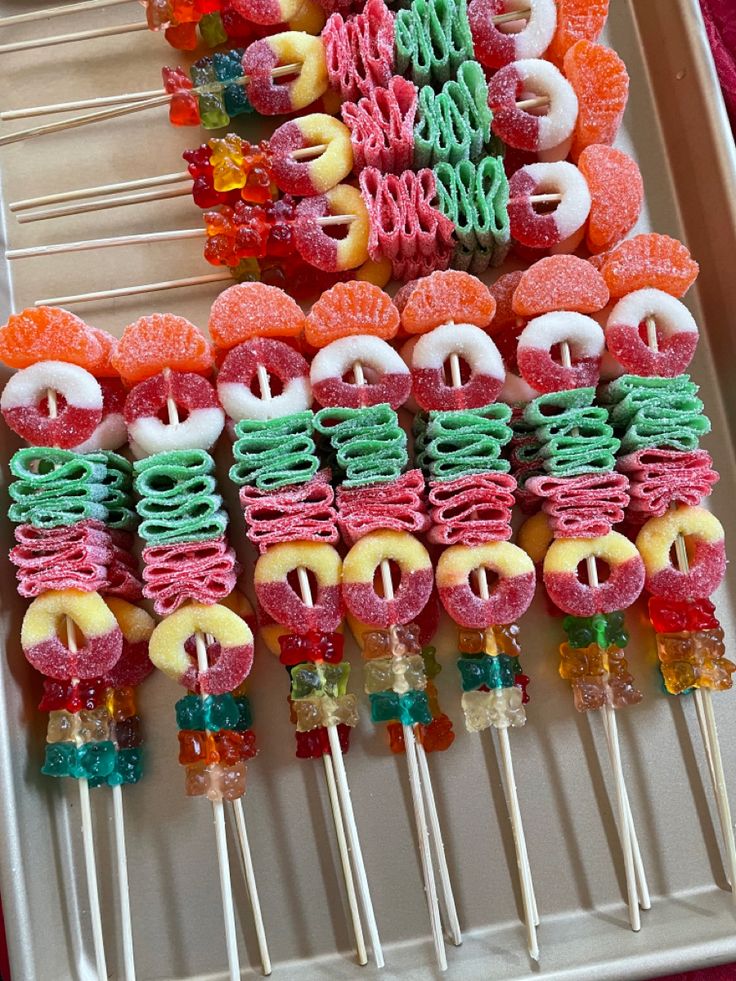 colorful candy lollipops are arranged on skewers in a tray for display